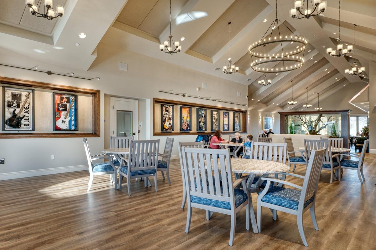 Moments of Lakeville great room with vaulted ceilings, chandeliers, and residents gathered at tables