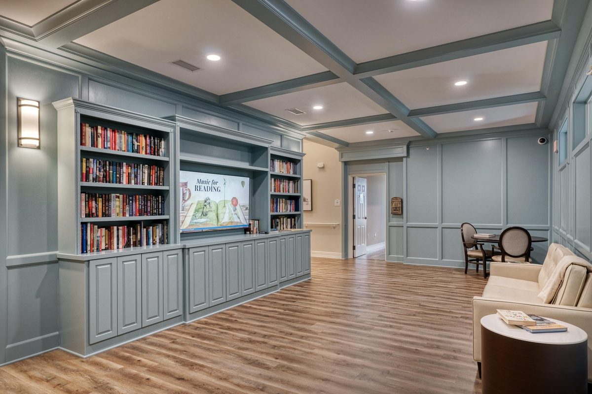 Moments of Lakeville reading room with built-in bookshelves, paneled walls, and a coffered ceiling